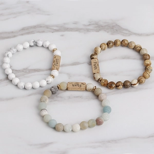 Detail of natural stone beaded bracelets featuring bronze metal bar engraved with Faith