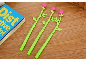 Close-up of three pink rose-shaped gel pens on a desk with floral stem design