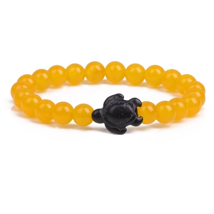 Detail of yellow round beaded elastic bracelet featuring a black carved turtle center bead