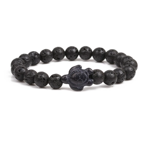Detailed view of lava stone beads and a turtle charm on this natural stretch bracelet