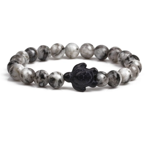 Macro detail of white marble beads and black sea turtle pendant on a stretch bracelet
