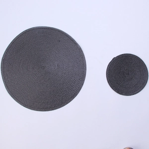 Detail of round dark gray woven heat-resistant placemats in two different sizes