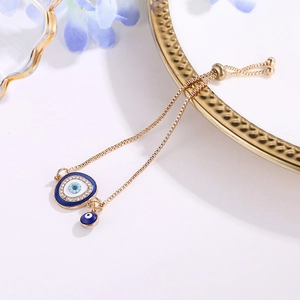 Detail view of gold evil eye bracelet with blue enamel and sparkling crystals on white background