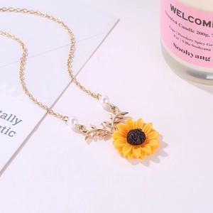 Détail d'un collier pendentif tournesol avec perles sur un fond blanc épuré