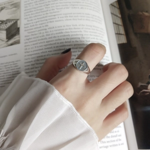 Close-up of vintage 925 sterling silver cross ring worn on finger with artistic background