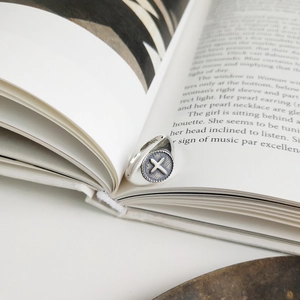 Macro shot of 925 sterling silver cross ring placed between open book pages with S925 stamp