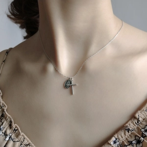 Close-up of vintage silver cross and oval religious icon pendant necklace on a model