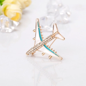 Elegant gold airplane brooch with white enamel and sparkling rhinestones on white base