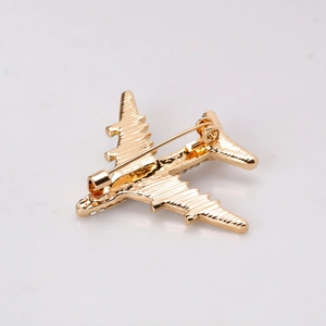 Golden airplane brooch with sparkling crystals and textured metal finish on white background