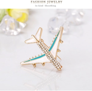 Detailed close-up of a golden airplane brooch with white enamel wings and sparkling rhinestones