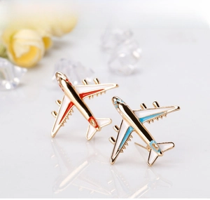Close-up of airplane enamel earrings in red and blue colors on a white surface