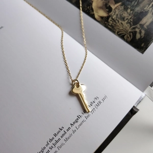 Artistic detail of a delicate gold key pendant necklace on an open book background