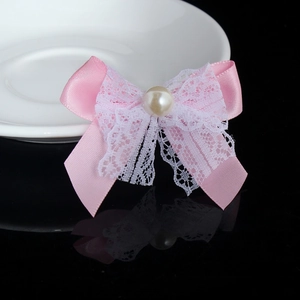 Close-up of pink satin and white lace bow accessory with a central pearl bead detail