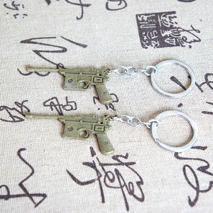 Macro shot of Mauser C96 pistol model keychains in vintage bronze on calligraphic fabric