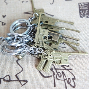 Macro detail of bronze metal Mauser C96 pistol miniature keychain on vintage fabric