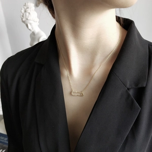 Close-up of gold safety pin necklace with sparkling white zircons on a black blazer