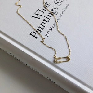 Detailed macro view of a gold safety pin necklace pendant set with shimmering crystals