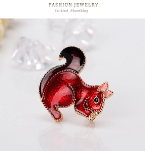 Detailed close-up of a cute red squirrel brooch with gold trim and pink bow accent