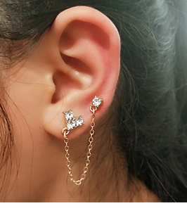 Close-up of gold cross chain earrings with sparkling zircons for double ear piercings