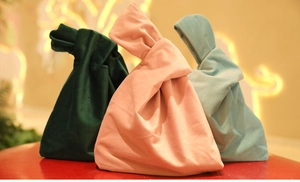 Detail of velvet gift bags with knot handles in green, pink and blue silk-like fabric