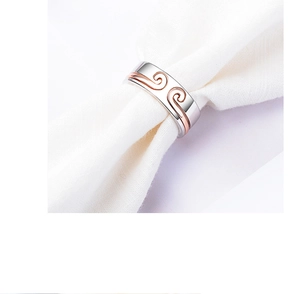 Detailed close-up of silver and rose gold metal ring with wavy texture on white fabric