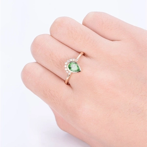 Close-up of a pear-cut green gemstone ring with round accent diamonds in rose gold