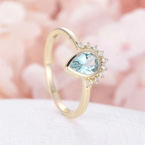 Macro detail of pear-cut light blue gemstone ring with delicate diamond accents