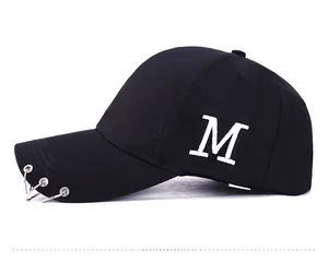 Détail d'une casquette noire en coton avec anneaux argentés et broderie M