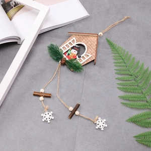 Detail of wooden Christmas house ornament with snowman pattern and pine needle accents