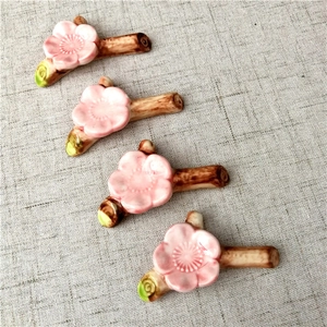 Set of 4 cherry blossom branch ceramic chopstick rests on grey linen fabric background