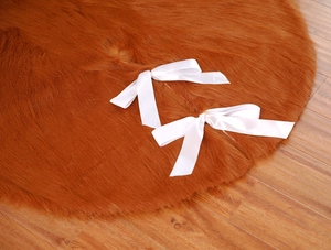 Detailed top view of soft brown faux fur Christmas tree skirt with white satin bows