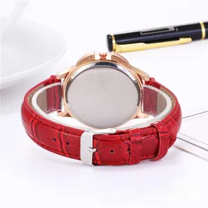 Detail of red leather watch strap and rose gold metal case with pin buckle closure
