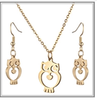 Detail of owl-themed jewelry set featuring a cutout heart gold necklace and hook earrings