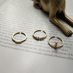 Three-piece set of gold-plated adjustable rings with zirconia crystals on vintage book