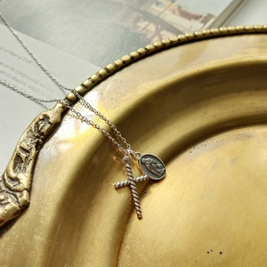 Vintage silver-tone double pendant necklace with a cross and saint medal on a gold tray