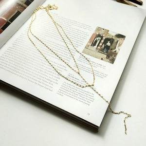 Elegant gold double-layered long necklace displayed on an open art book page