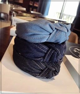 Detailed view of three knotted denim headbands in light blue, dark blue, and black fabrics