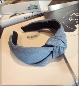 Close-up of blue denim knotted headband featuring orange double stitching and texture