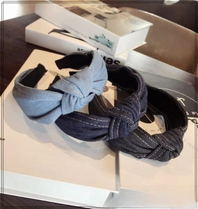 Close-up of knotted denim headbands in light, medium, and dark blue with white stitching