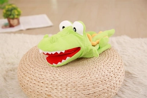 Detail view of a green plush crocodile hand puppet resting on a woven straw mat
