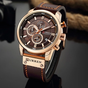 Detail of rose gold chronograph watch with brown leather strap and orange contrast stitching