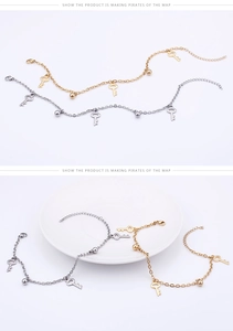 Detailed close-up of gold and silver key charms and spherical beads on anklet chains