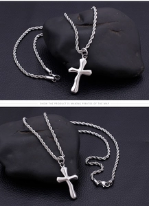 Detail of stainless steel cross pendant featuring twisted rope chain and metal stamp