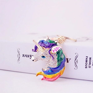 Golden unicorn keychain with rhinestones and colorful enamel detailing on white surface