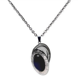 Macro detail of vintage silver locket with blue gemstone and ornate floral engravings