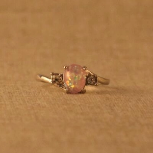 Detailansicht eines ovalen Opals in einem goldenen Ring im Vintage-Stil mit Seitensteinen