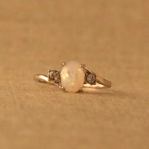 Eleganter versilberter Opalring mit ovalem weißem Stein und Diamantakzenten auf gelbem Grund