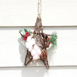 Star-shaped Christmas wreath detail with pine cones berries and cotton on rustic vine