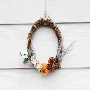 Handmade rattan wreath with golden berries, orange sunflowers, and pine cones detail