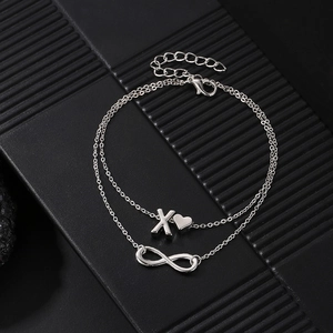 Macro shot of double-layer silver infinity chain with heart and letter X charm